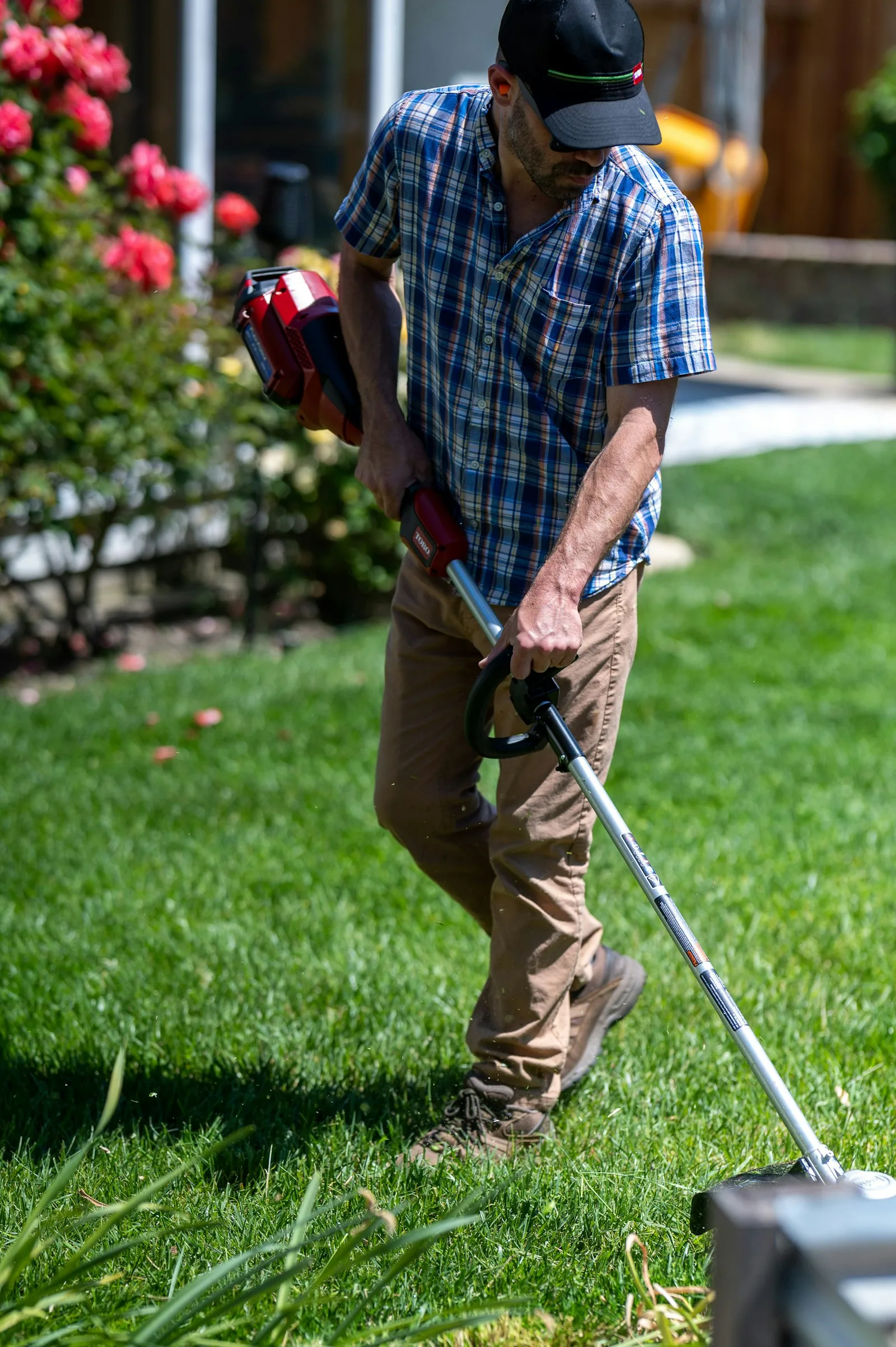 A man using a lawn mower to cut grass